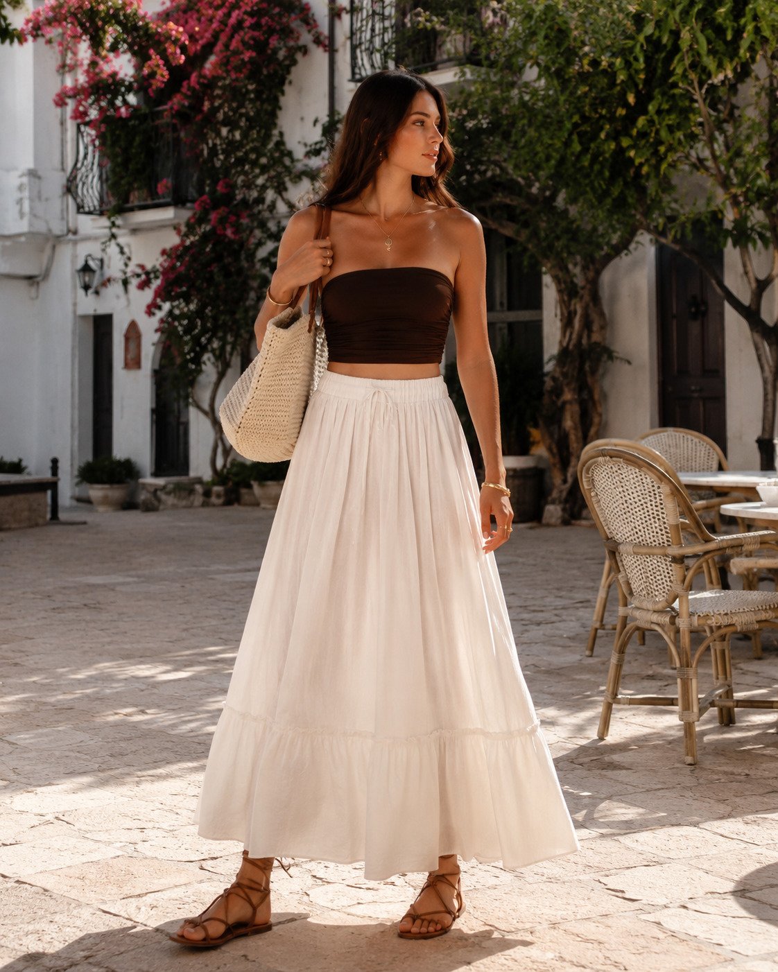 Woman in a chocolate bandeau top with an ivory poplin maxi skirt in a Mediterranean village square